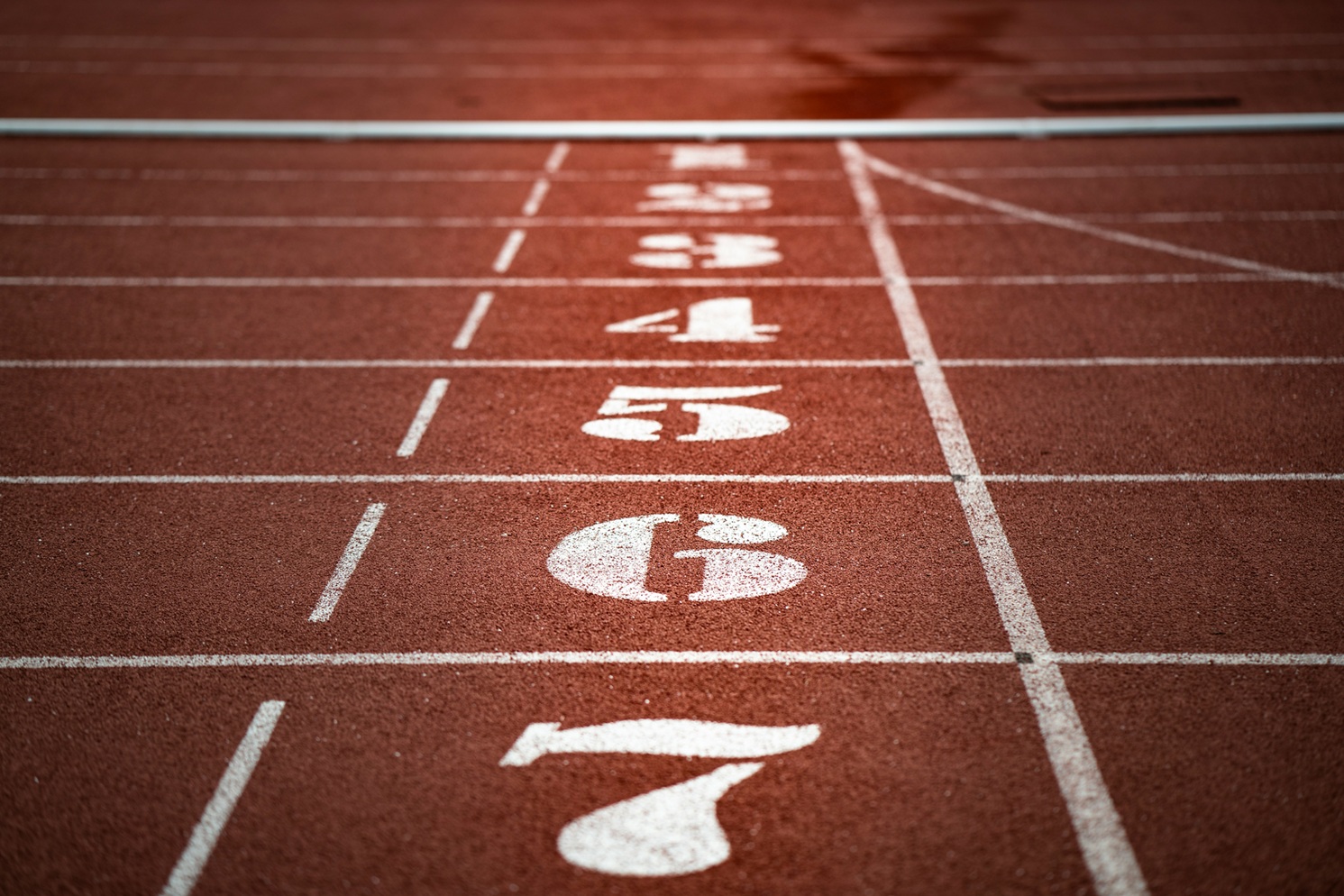Startlijn van een atletiekbaan met nummers 1 tot 7