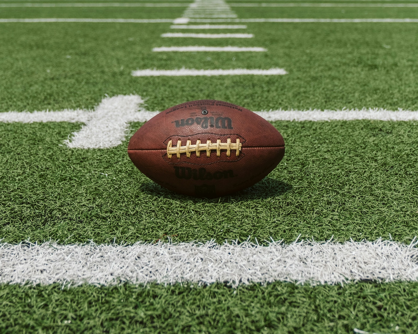 Een american football op een grasveld met witte lijnen.