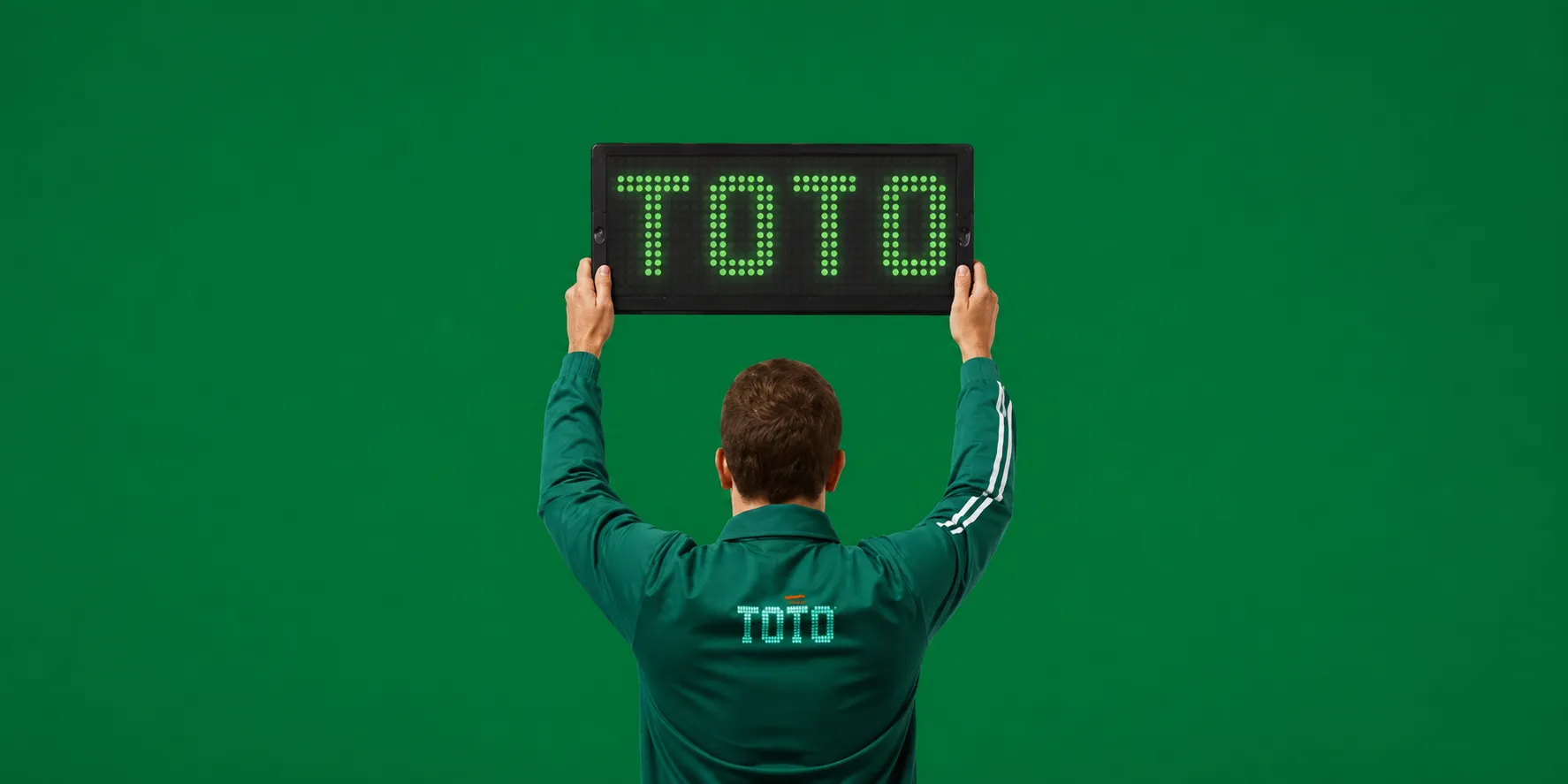 Man met TOTO jas houdt bord vast met TOTO logo