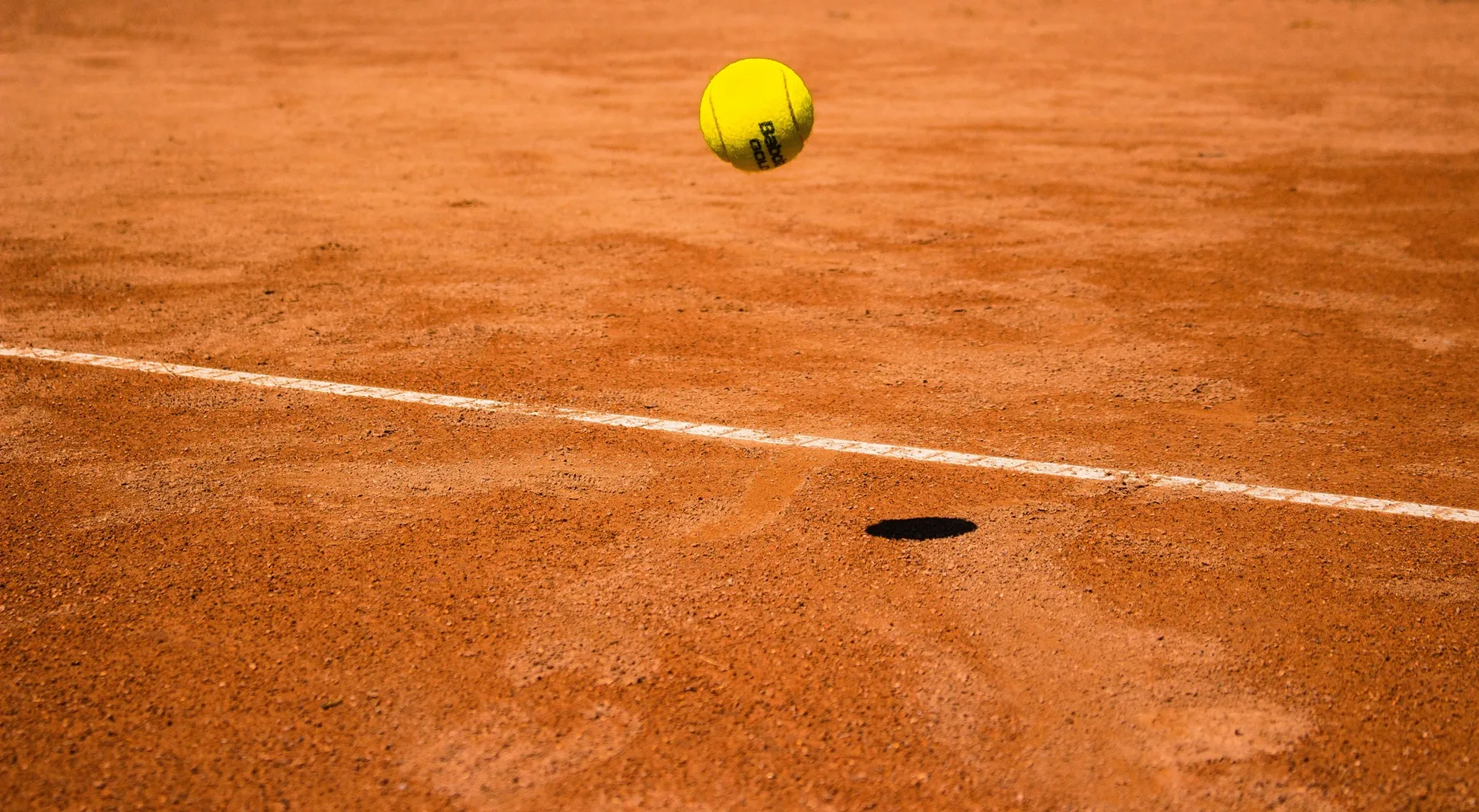 Tennisbal in de lucht boven gravelbaan