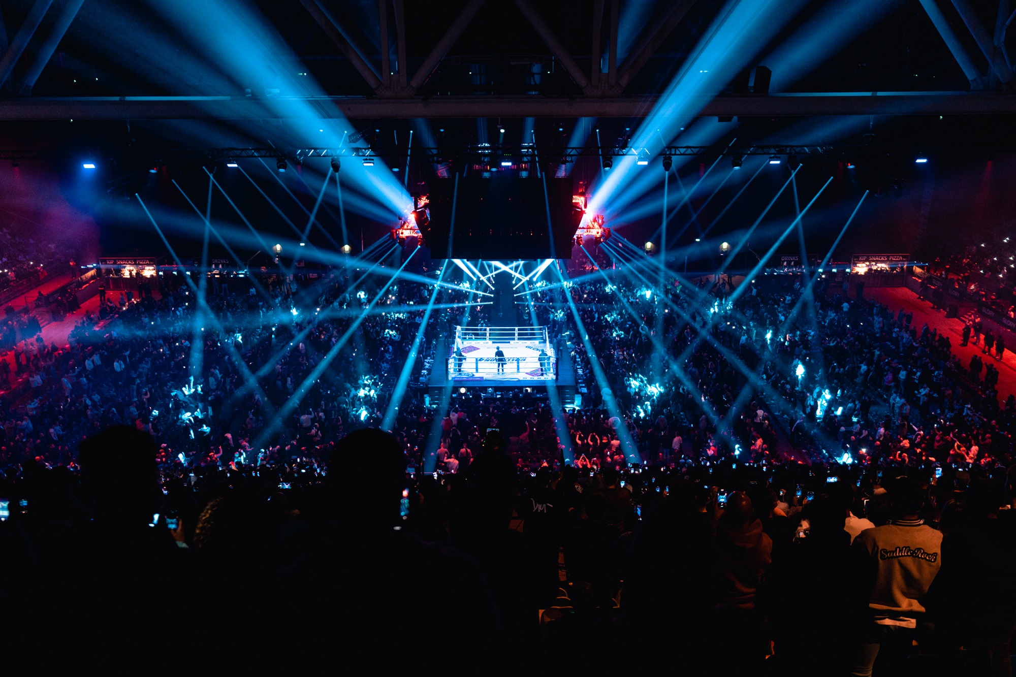 Een arena vol lichten met in het midden een ring voor GLORY-gevechten.