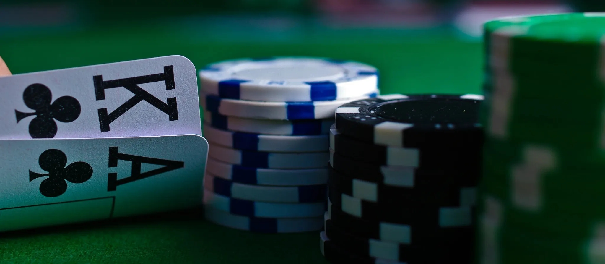 Close-up van een pokerhand met een Aas en Koning, naast stapels gekleurde fiches op een groene speeltafel