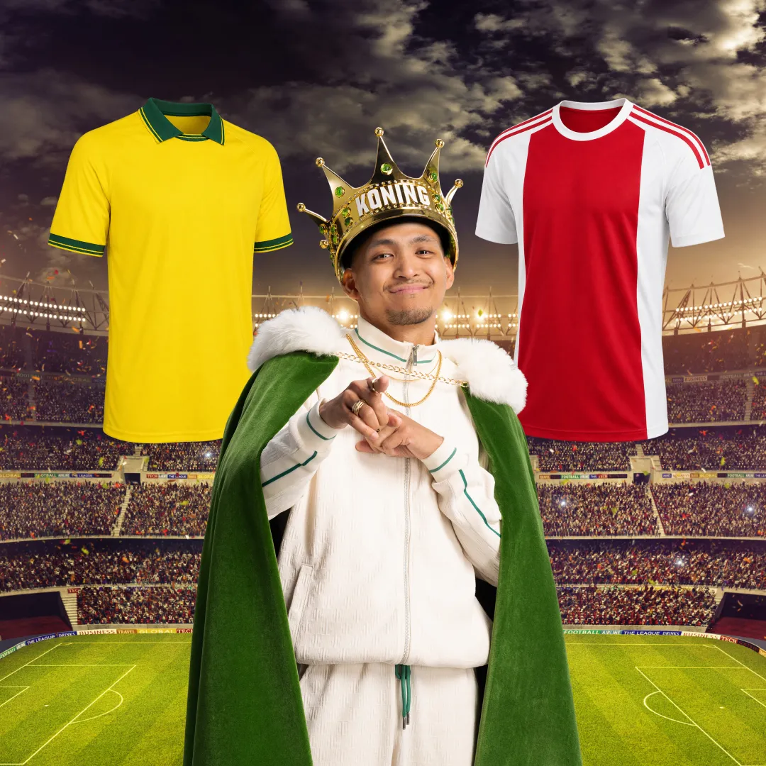 Man met koningskroon en groene mantel tussen gele en rood-witte voetbalshirts in stadion