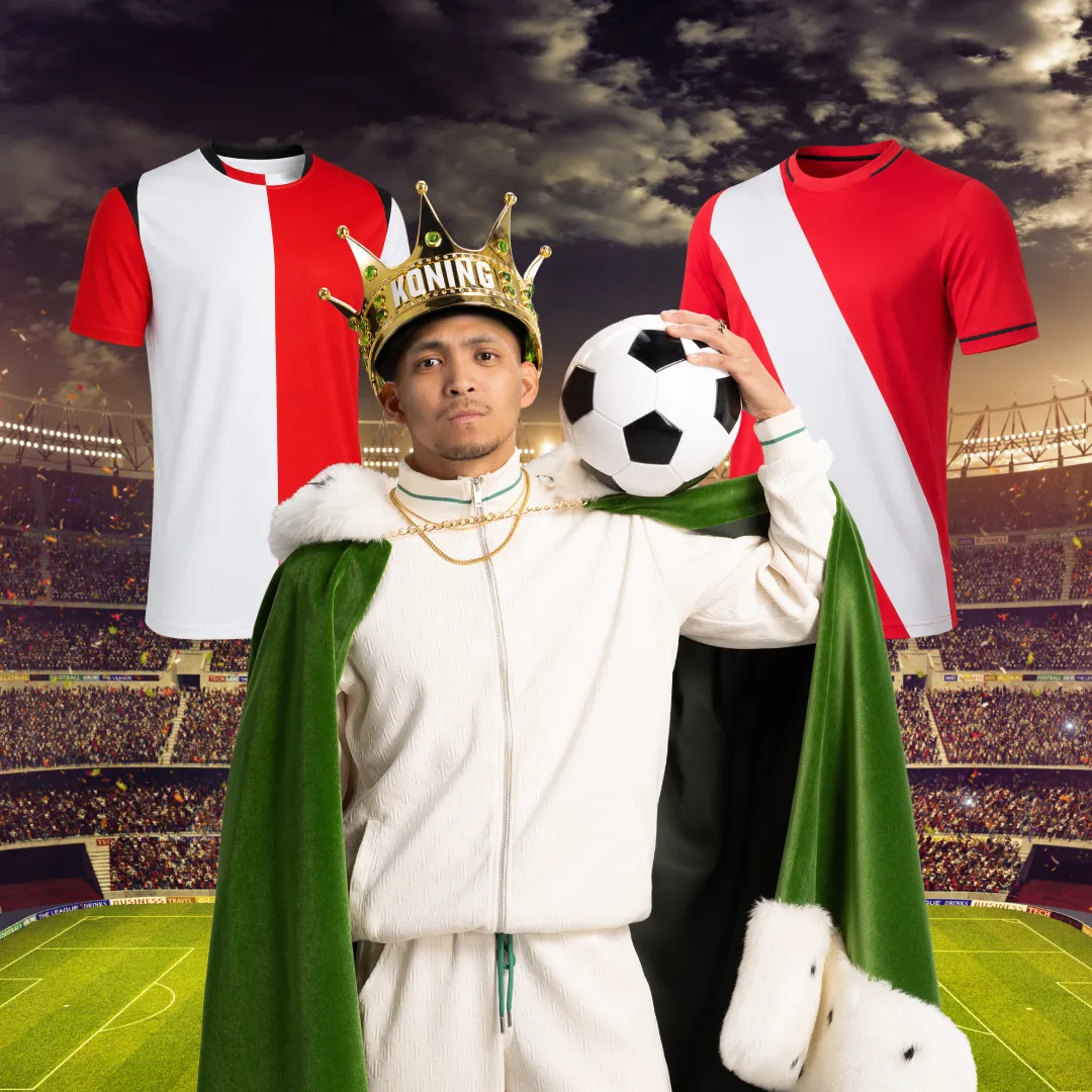 Man met kroon en groene koningsmantel, houdt voetbal vast, met rood-witte voetbalshirts op achtergrond in stadion