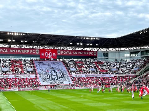 Sfeeractie met rood-witte kaarten en groot spandoek bij Royal Antwerp FC in een vol stadion