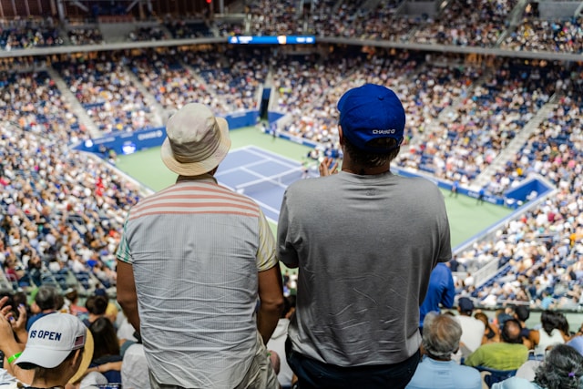 Twee toeschouwers bekijken een wedstrijd van de US Open in een stadion.