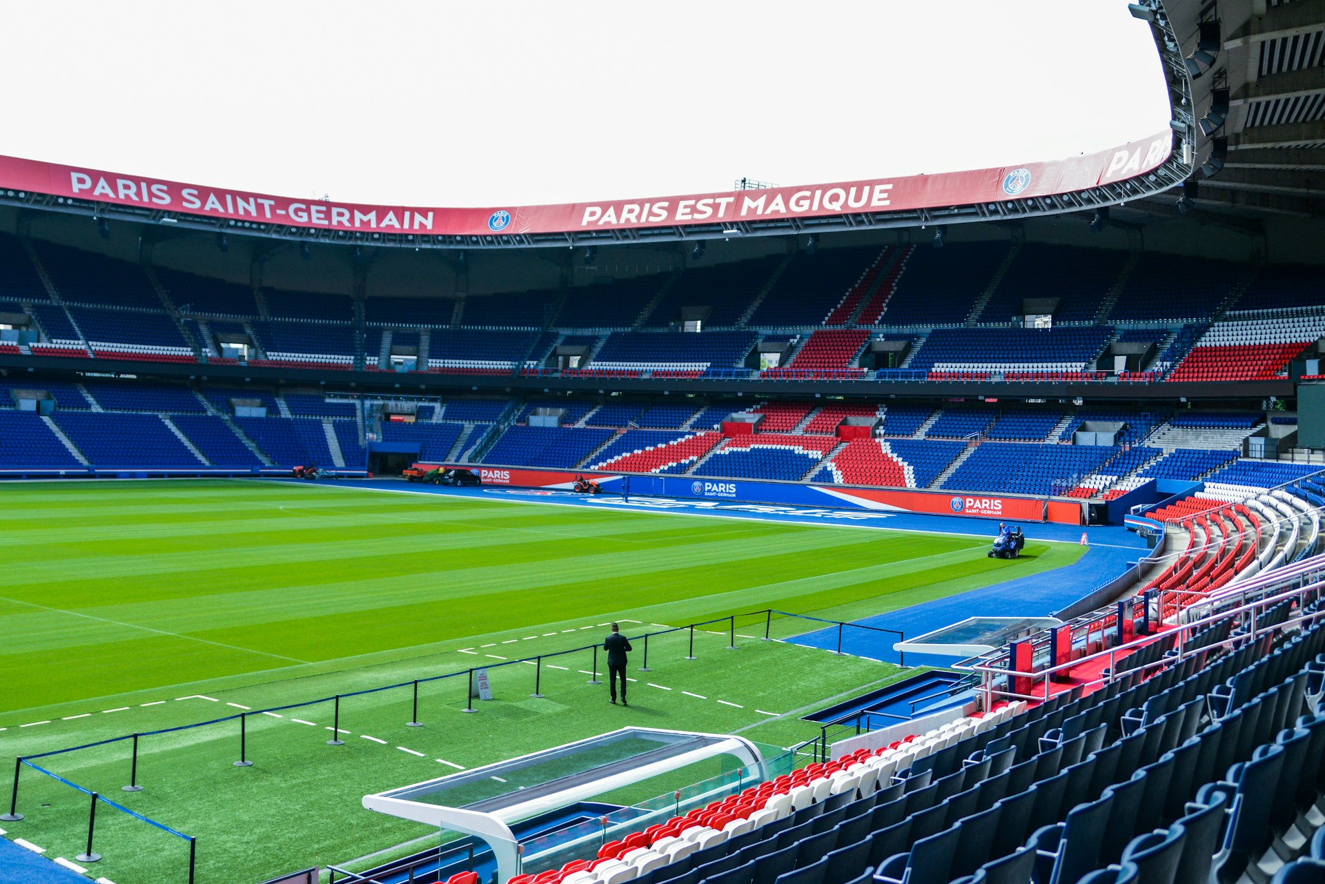 Uitzicht op een leeg Parc des Princes met rode, witte en blauwe stoelen en PSG-logo’s rondom het veld