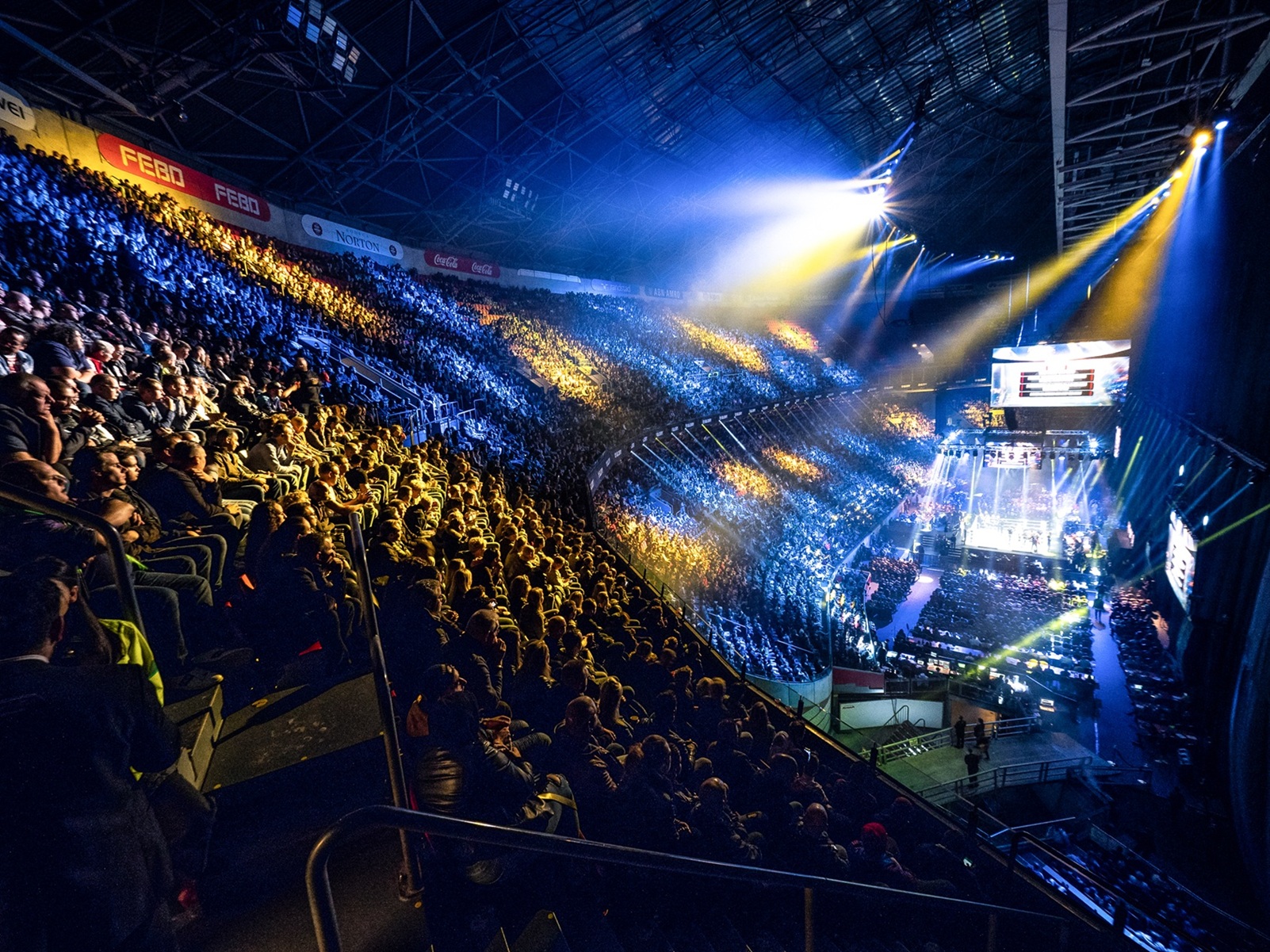 Een verlichte arena vol publiek met in het midden een ring voor GLORY-gevechten