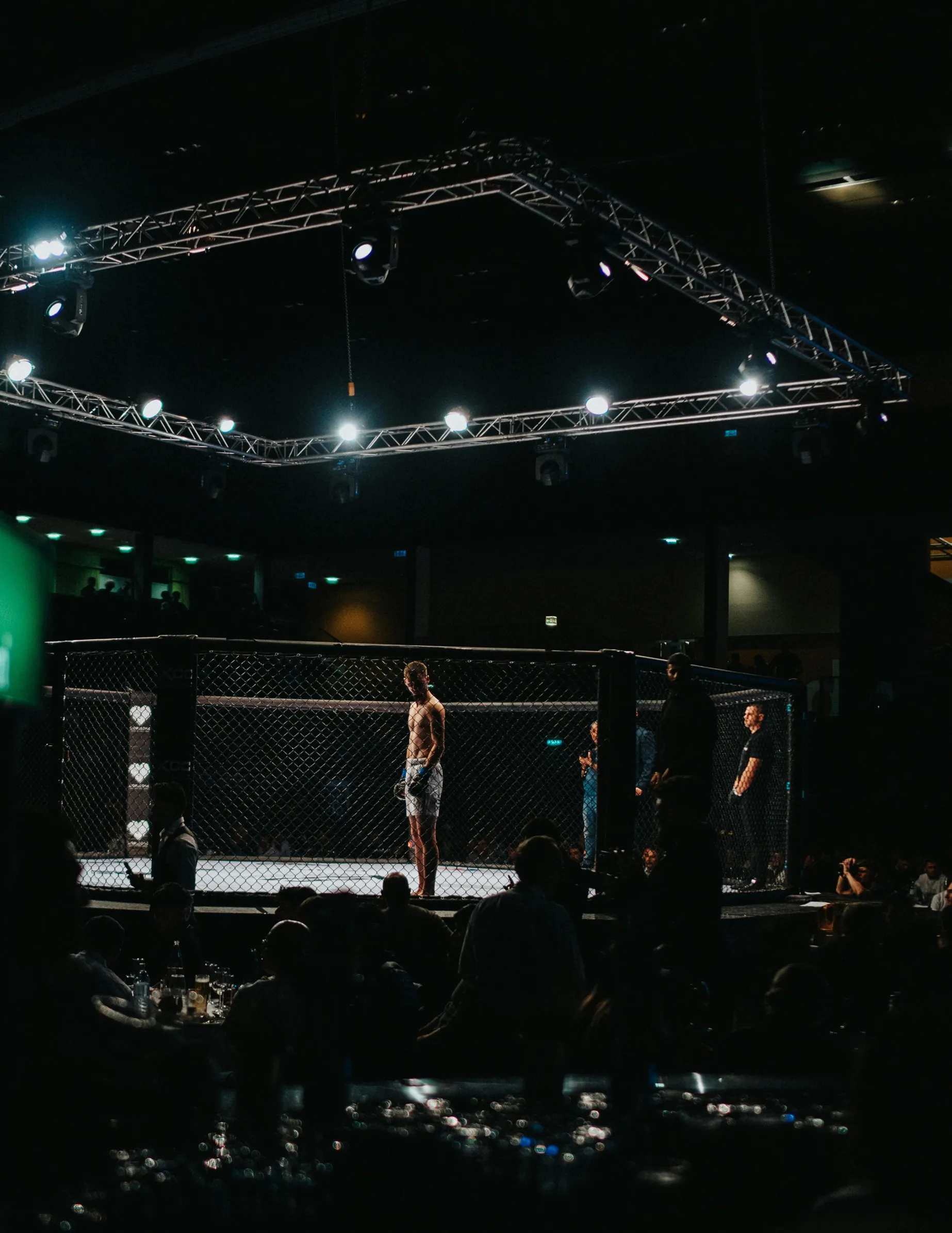 Vechtkampioen in kooi tijdens MMA-wedstrijd met publiek in de zaal