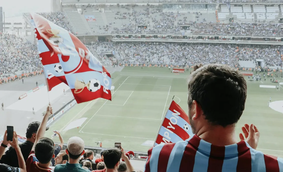 Trabzonspor-fans met vlaggen en kampioensshirts juichen in een vol stadion