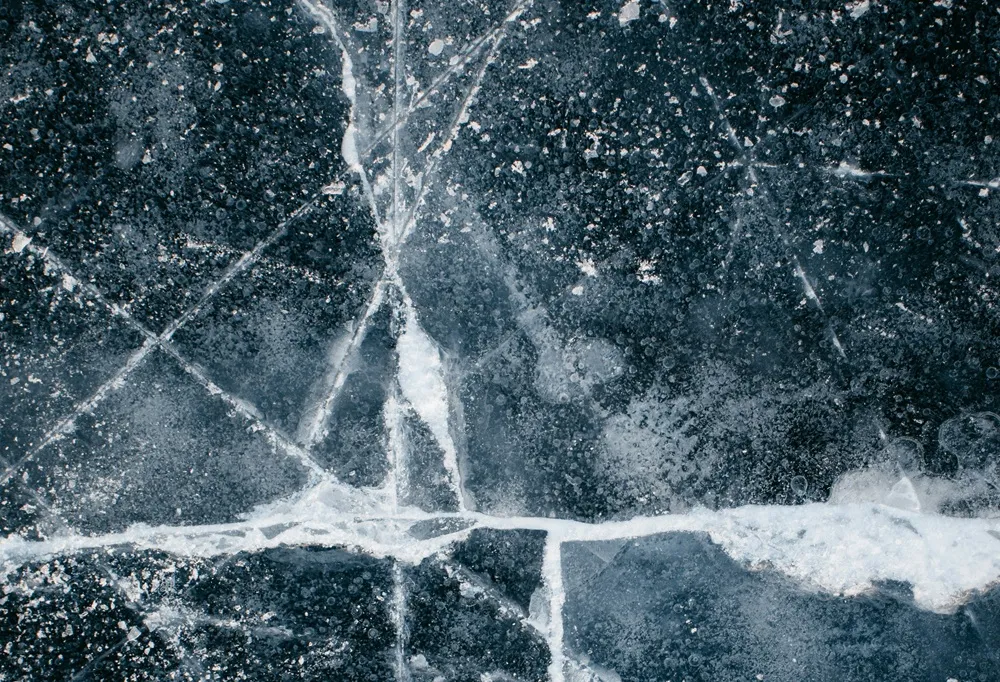 Gekleurde, gebarsten ijsoppervlakte met luchtbellen