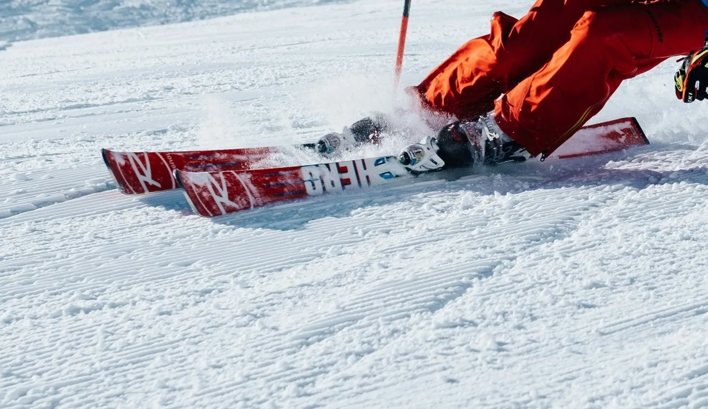 Skiër in een rode outfit die van een sneeuwhelling afdaalt
