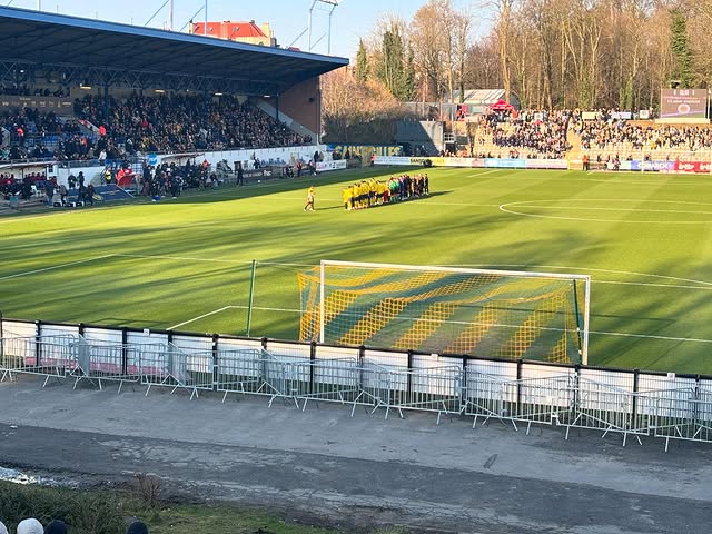 Zonovergoten wedstrijdmoment in het Joseph Marien Stadion met zicht op het veld en de volle hoofdtribune van Union SG