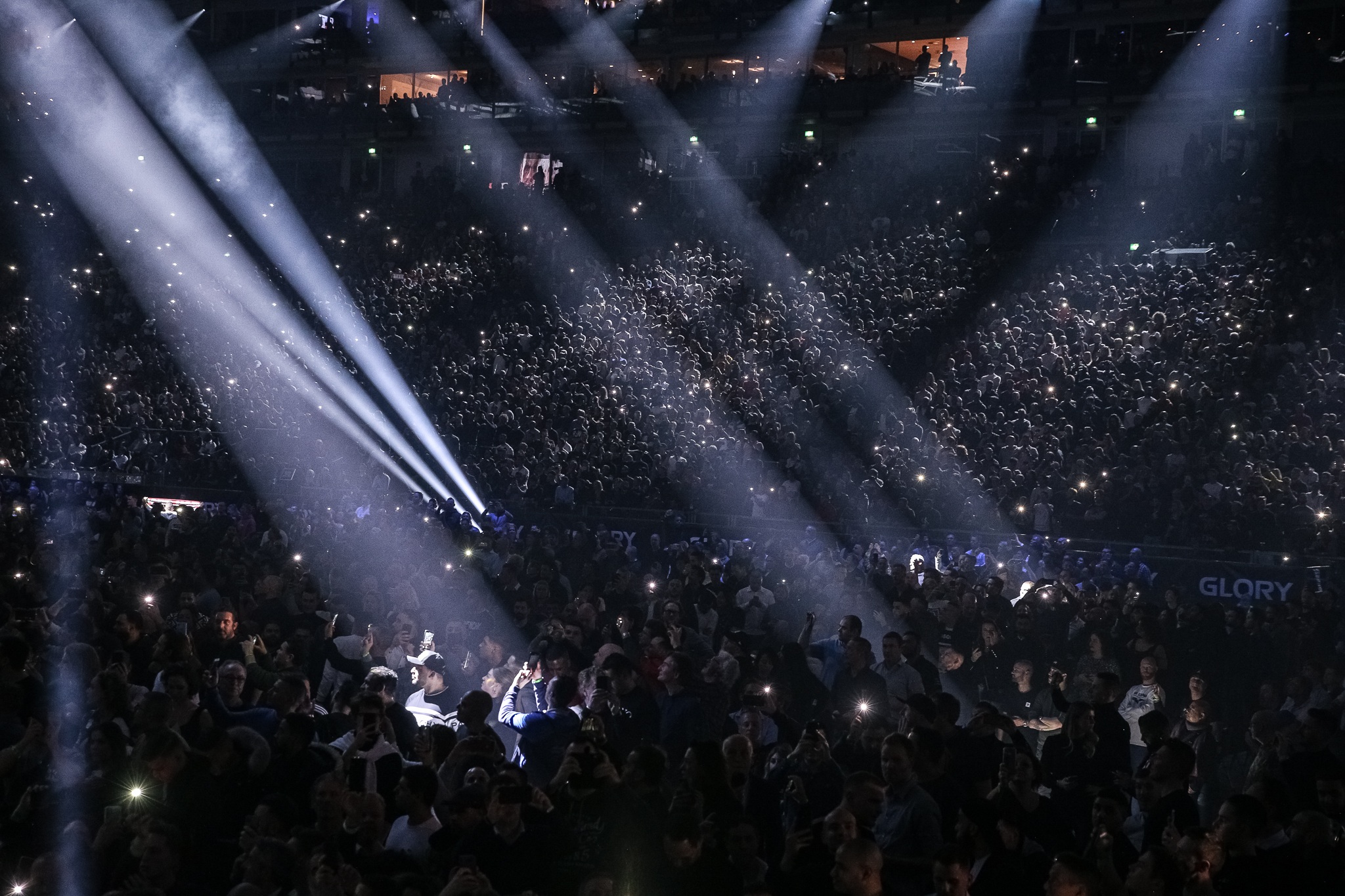 Een sfeervol verlichte arena vol fans die kijken naar een GLORY-gevecht